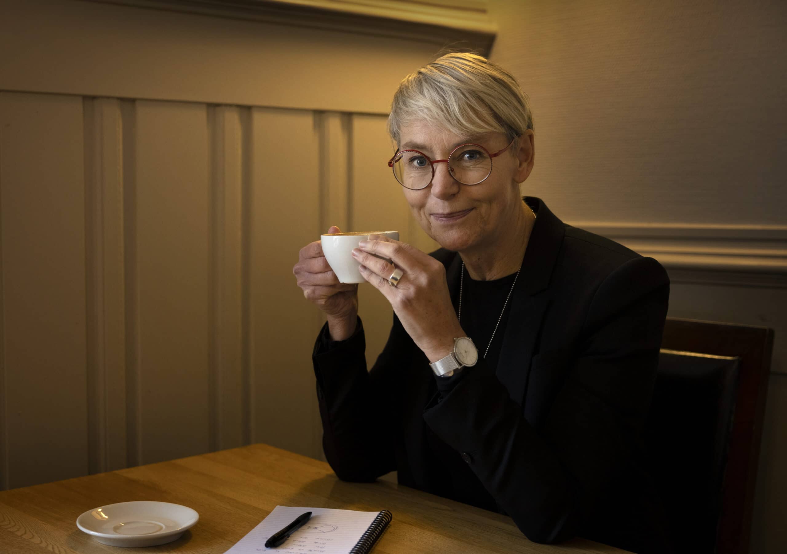 En tre-stegs-guide för att reflektera.Kvinna som sitter vid bord, dricker kaffe och skriver.